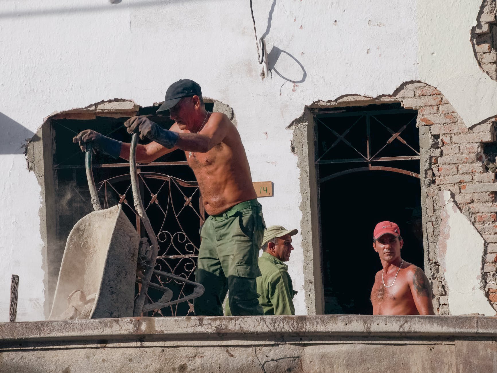 shirtless men working on balcony of old building