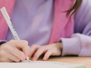 concentrated young lady taking notes in planner while doing assignment in university