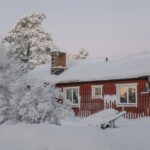 a red house covered in snow next to trees