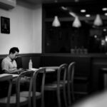 man sitting on cafe while holding smartphone